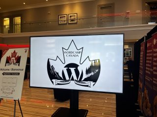 WordCamp Canada logo on large monitor in hall of the conference centre